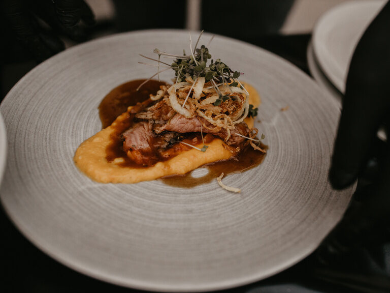 Ein kunstvoll angerichtetes Fleischgericht auf einem Teller.