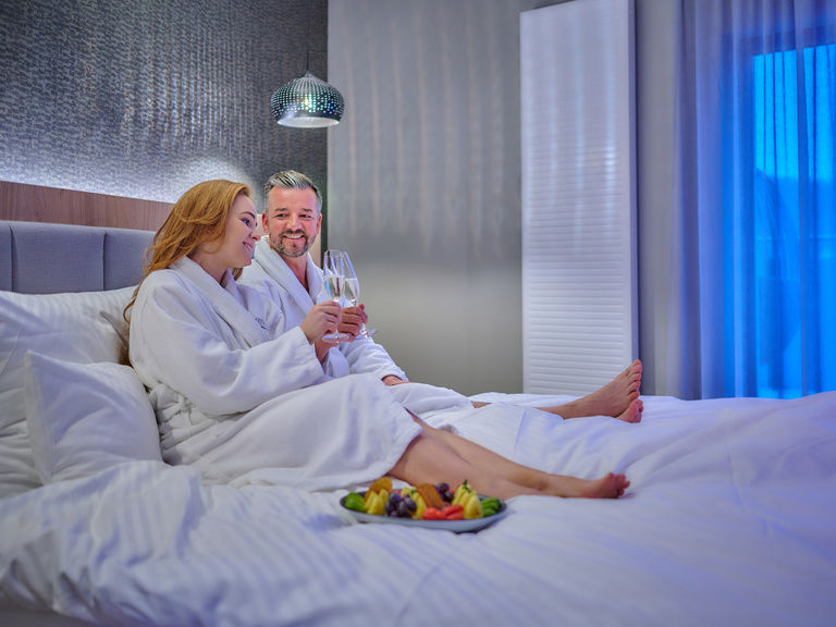 Ein Paar stößt im Bett an.