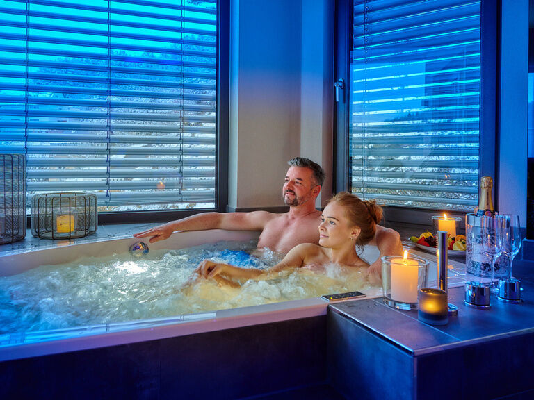 Ein Paar entspannt in einem luxuriösen Whirlpool in ihrer Wellness-Suite.