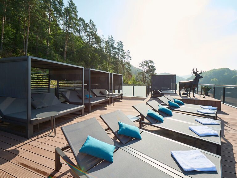 Liegen stehen auf einer Dachterrasse neben der Skulptur eines Hirsches