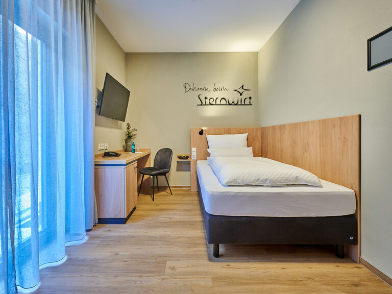 Ein gemütliches Hotelzimmer mit einem eleganten Bett und schlichtem Schreibtisch.