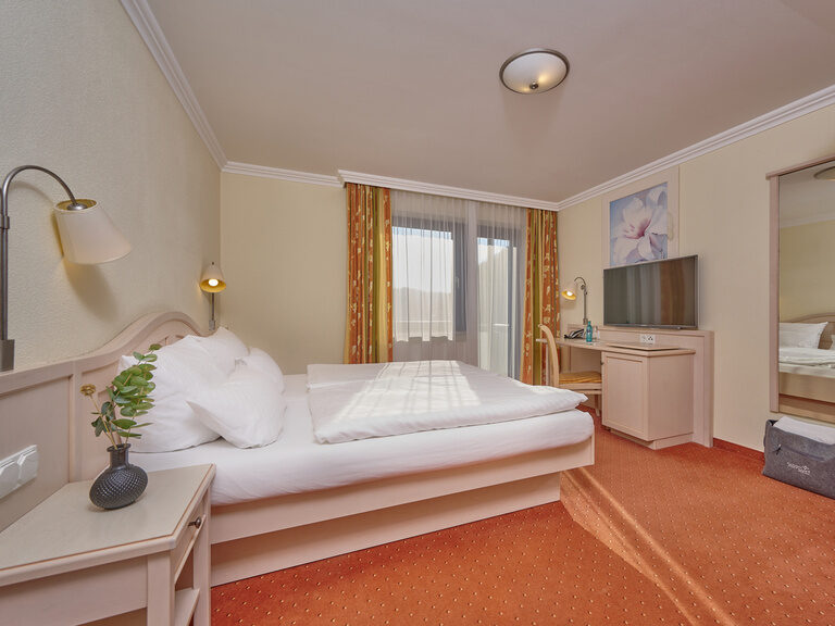 Ein geräumiges Zimmer mit einem luxuriösen Bett und einer schicken TV-Option, ideal für Entspannung.