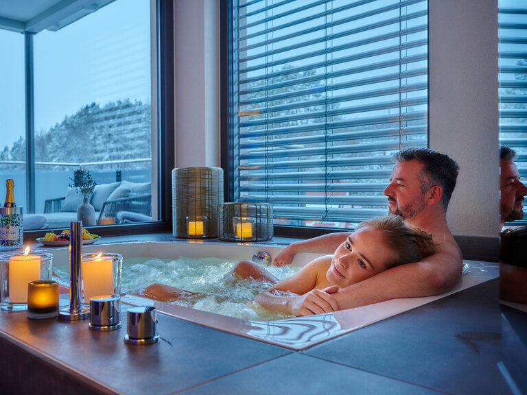 Ein Paar sitzt gemütlich in einer Badewanne im Hotelzimmer.