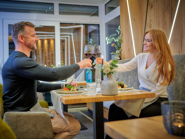 Ein fröhliches Paar genießt kulinarische Erlebnisse in einem eleganten Restaurantambiente.